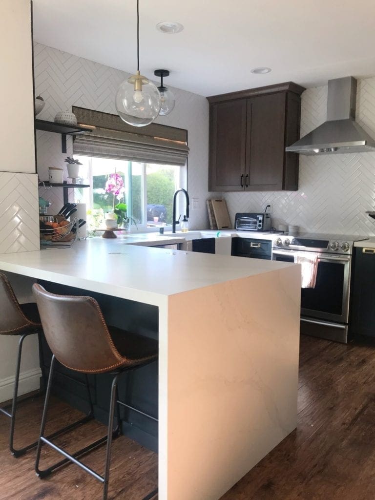 Before and After Kitchen Renovation with ideas and costs. See our farmhouse sink, herringbone backsplash with white subway tile and our DIY open shelving without changing our layout. Two-tone cabinets in woodgrain and blue. Including tips to get the most out of your budget. #kitcheremodel 