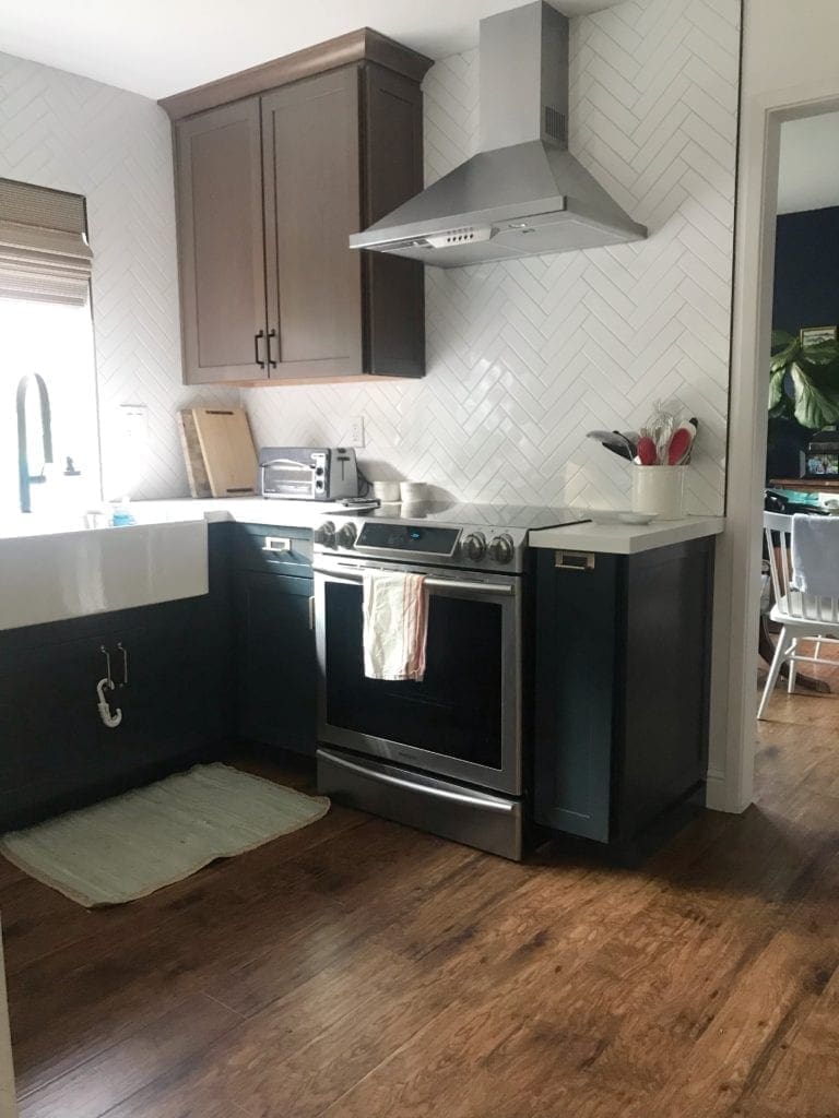 Before and After Kitchen Renovation with ideas and costs. See our farmhouse sink, herringbone backsplash with white subway tile and our DIY open shelving without changing our layout. Two-tone cabinets in woodgrain and blue. Including tips to get the most out of your budget. #kitcheremodel 
